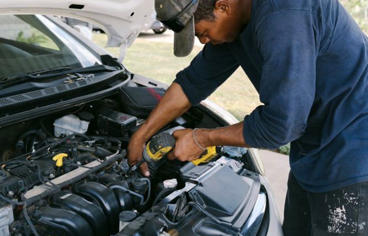 Mechanic changing oil on a sedan in a Bartlett neighborhood driveway